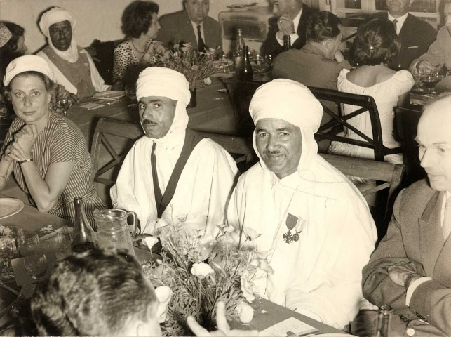 Deux targuis et une femme assis à table.
