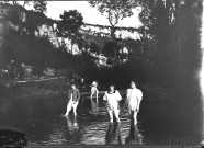 Groupe de quatre femmes les pieds dans l'eau d'une rivière.