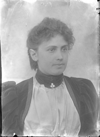 Jeune femme en robe de velours et broche en trèfle.