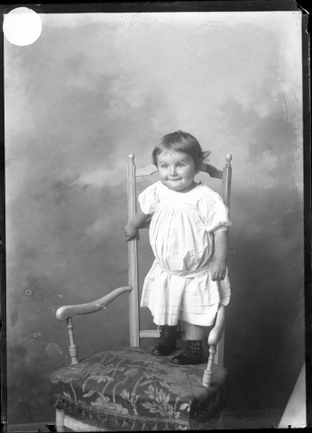 Bambin autour de 2 ans debout sur un fauteuil.