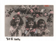 Trois fillettes sous une guirlande de fleurs.