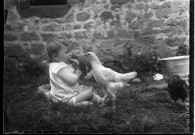 Assise dans le jardin, mangeant un bout de pain, une poule s'approche d'elle.