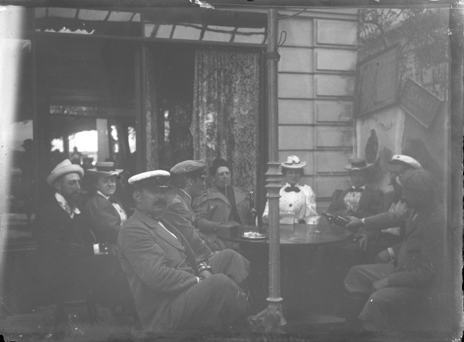 Groupe d'hommes et de femmes attablés sur la terrasse d'un café.