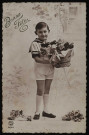 Jeune garçon en tenue de marin portant un panier rempli de fleurs.